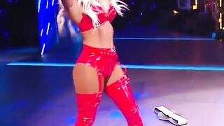 WWE - Carmella in red outfit standing over Sasha Banks