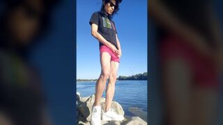 Twink boy with long dark hair pissing pee on the river dressed in glasses cap sneakers boxer tshirt